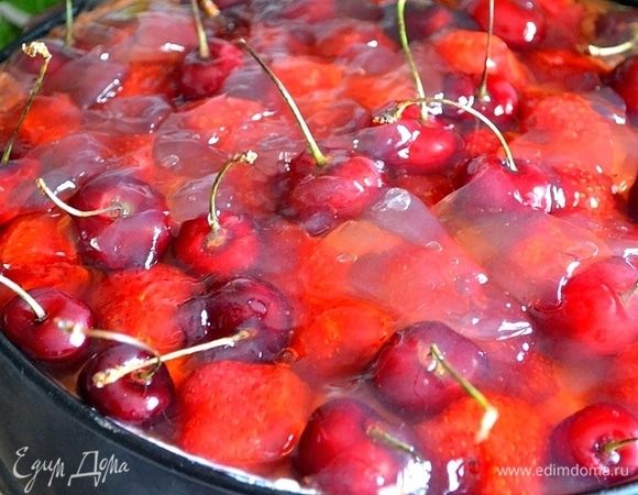 Уже через час сливочный слой как следует застыл. Готовим верх чизкейка: укладываем нарезанную клубнику и черешню. В соответствии с инструкцией на пачках готовим желе для торта. Я развела в горячей воде (400 мл) клубничный джем, желе из пачек и проварила 15 секунд после закипания, постоянно помешивая. Процедила желе через марлю. Желе остывает и схватывается очень быстро. Постоянно помешивала, пока остужала. Теплым желе аккуратно поливаем каждую ягоду. Потом выливаем полностью желе и ставим форму в холодильник. Идеально, если на ночь.