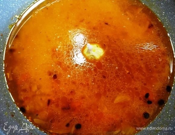 Аккуратно выливаем горячий бульон на рис, в центр устанавливаем головку чеснока. Как только бульон закипел, уменьшаем мощность плиты на минимум, накрываем рис крышкой и томим 20 минут. По прошествии времени снимаем сковороду с горячей конфорки, накрываем двумя полотенцами и оставляем рис до готовности баранины.