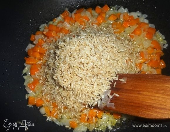 Рис предварительно промыть под проточной водой, дать воде стечь. Положить рис в сковороду с обжаренными морковью и луком, перемешать. Продолжать обжаривать все вместе еще 5 мин.