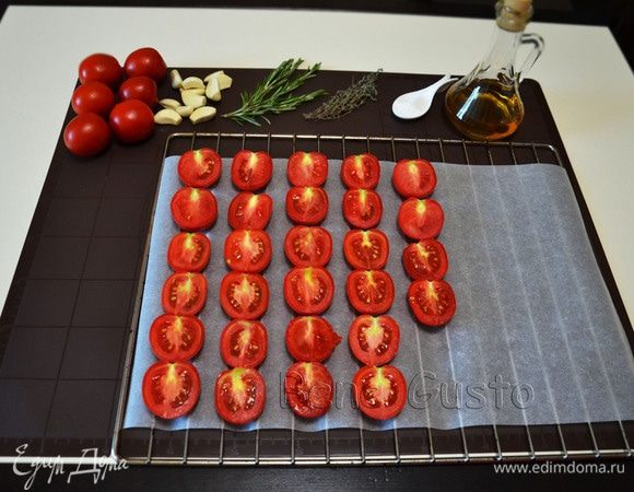 Решетку или противень застилаем пергаментом. Томаты разрезаем пополам и выкладываем срезом вверх.