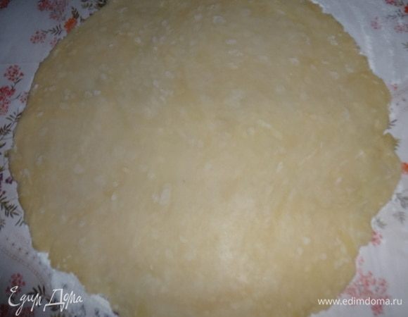 Достать тесто из холодильника. На стол насыпать 1 ч. л. муки, раскатать тесто в круг диаметром немного больше диаметра формы.