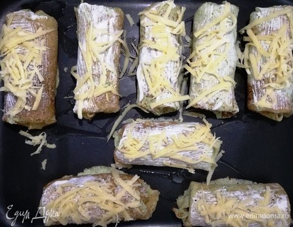 Выкладываем подготовленные блинчики на противень. Смазываем сметаной, посыпаем сыром.