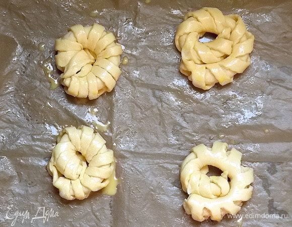 Уложить на застеленный бумагой для выпечки противень. Смазать желтком и посыпать сверху сахаром.