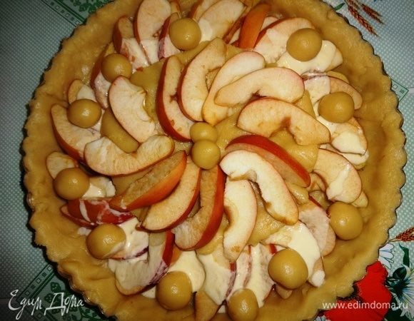 От оставшейся части теста отделить небольшой кусочек и раскатать круг по диаметру равный половине диаметра дна. Яблоки, уложенные на дно, полить небольшой частью заправки. Выложить круг из теста поверх яблок посередине. На него выложить остальные яблоки. У меня еще осталось немного теста, я сделала из него маленькие шарики и уложила на пирог в произвольном порядке.