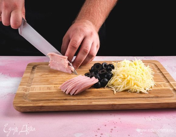 Сыр натрите на терке, ветчину нарежьте соломкой, маслины — пополам.<br />