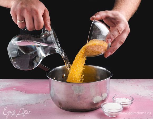 В кастрюлю налейте воду. Всыпьте кукурузную крупу.  Добавьте сахар, соль, доведите до кипения, уменьшите огонь до минимума, и варите крупу в воде до тех пор, пока вода полностью не впитается. Периодически помешивайте кашу.