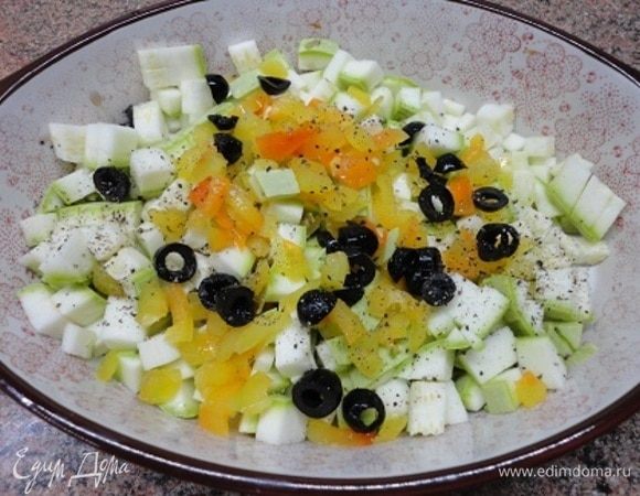 Молодой кабачок нарезать кубиками вместе с кожицей. Также нарезать перец и оливки колечками. Форму смазать оливковым маслом, выложить овощную смесь и сбрызнуть оливковым маслом.