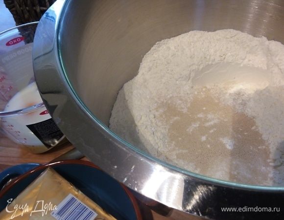 Сливочное масло понадобится размягченное, потому его нужно вынуть из холодильника заранее. Соединить муку, разрыхлитель, щепотку соли, дрожжи и сахар. Добавить яичные желтки, молоко и воду.