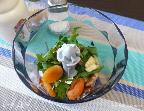 В чашу блендера сложить курагу, чеснок, грецкие орехи, петрушку.