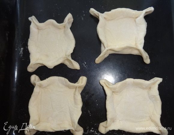 Выложить заготовки из теста на противень, смоченный водой. У каждого квадрата теста прищипнуть краешки-«ушки». Только смотрите, чтобы они хорошо слепились между собой. А то у меня в процессе выпечки у 2 слоек немного разошлись края.