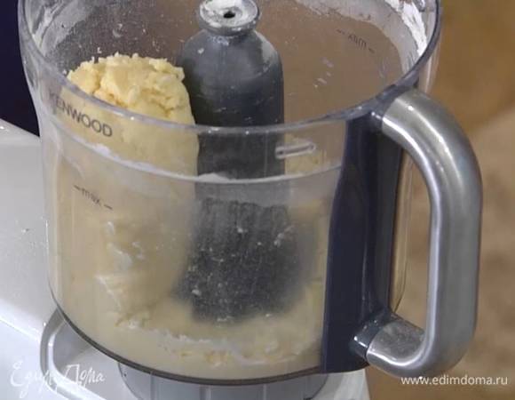 Приготовить тесто: 100 г предварительно охлажденного сливочного масла нарезать небольшими кубиками и выложить в чашу комбайна, добавить муку, сахарную пудру, крахмал, соль и измельчить все в крошку, затем, не выключая комбайна, влить по одной ложке холодное молоко, чтобы тесто сбилось в шар.