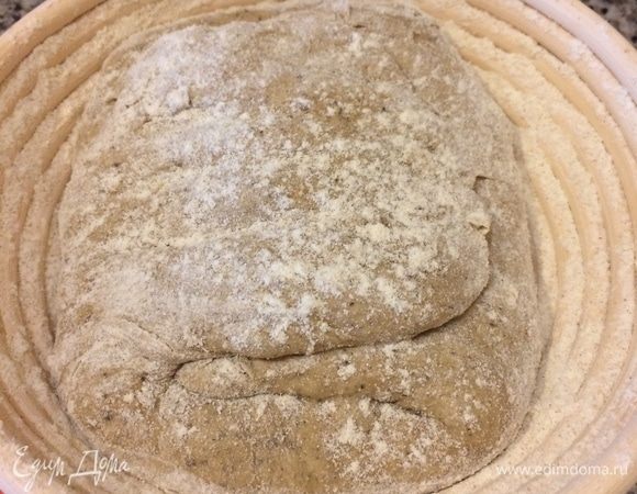 Затем корзинку для расстойки хлеба хорошо присыпать мукой, переложить хлеб в корзинку швом вверх, накрыть и оставить на полтора часа. Пока тесто отдыхает, ставим чугунок в духовку и нагреваем ее до 220°C.