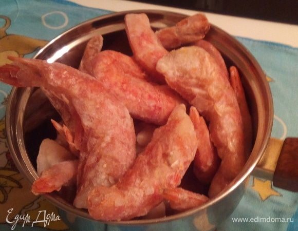 Мороженые креветки обдать кипятком над дуршлагом. Смешать на разогретой сковороде растительное и сливочное масла, соль и черный молотый перец, переложить туда креветки.Обжарить 10 минут, постоянно помешивая. Нарезать зелень по вкусу.