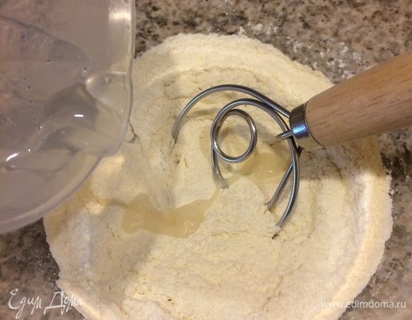 Просеять в миску все три вида муки, добавить соль и перемешать. Сделать в муке лунку, добавить слегка теплую воду.