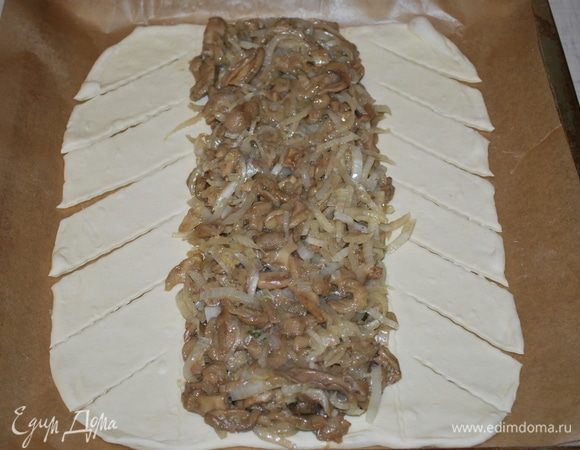 Раскатать слоеное тесто, выложить на середину начинку и надрезать тесто полосками.