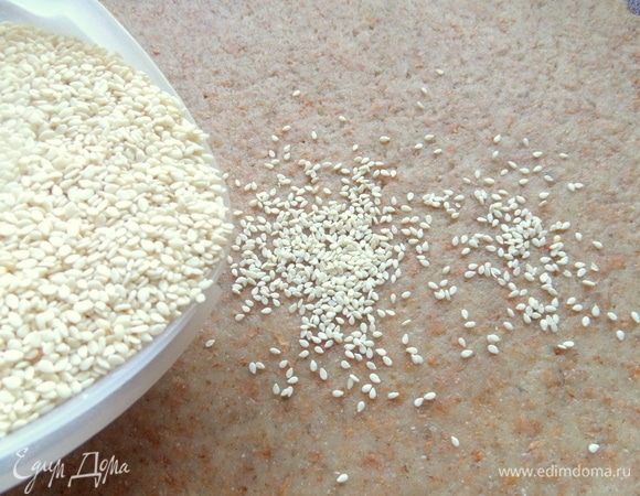 На доске или коврике раскатать тесто в пласт, насыпать кунжут или другие семечки, орешки.