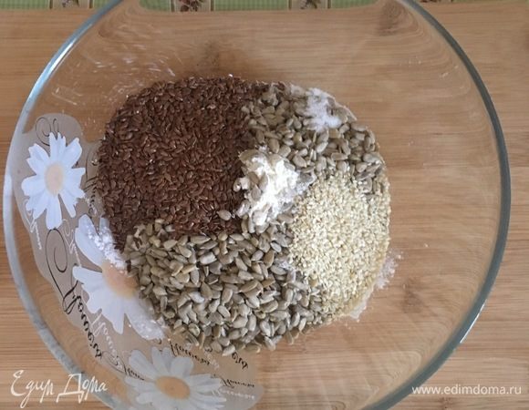 Разогрейте духовку до 180°C. В большой миске смешайте все сухие ингредиенты: муку, семена, соль.
