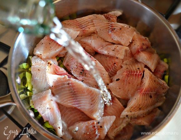 Филе тилапии выложите поверх обжаренного порея с чесноком, залейте белым вином, накройте крышкой и тушите на слабом огне 8–10 мин.