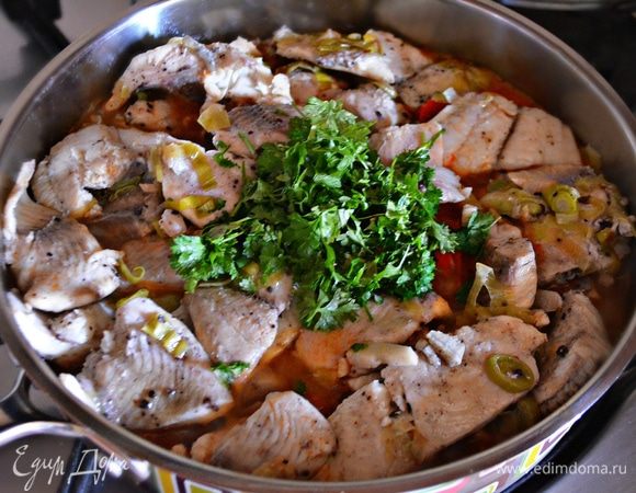 На тушеные овощи аккуратно выложите рыбное филе с луком и чесноком, добавьте рубленную петрушку, накройте крышкой и тушите еще 3–5 мин.