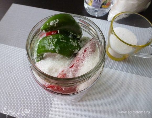 Уложили мы острый перец и чеснок в банку и засыпаем сахар. Сразу он весь не поместится, поэтому его всыпаем частями. Слегка постукиваем донышком банки по столу, чтобы сахар заполнил все пустые места.