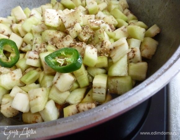 Выкладываем слегка отжатые от влаги баклажаны, всыпаем кориандр и чили (по вкусу).