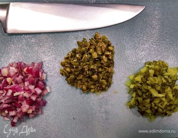 Мелко рубим каперсы, маринованные огурцы и лук. Багет нарезаем ломтиками и отправляем подсушиться в духовой шкаф на 10 минут. Можно вместо багета использовать тостовый хлеб.