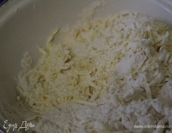 В широкую миску или на стол высыпать просеянную муку, положить сверху холодное масло и порубить ножом в крошку.