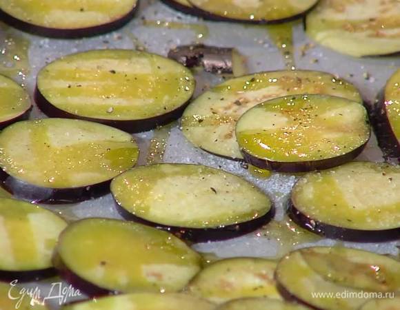 Баклажаны нарезать тонкими кружками, выложить на противень, выстеленный пищевой бумагой, сбрызнуть 1–2 ст. ложками оливкового масла, посолить, поперчить и запекать в разогретой духовке 10–15 минут.