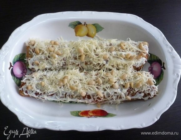 Смазываем рулетики сметаной, посыпаем натертым сыром и кедровыми орешками.