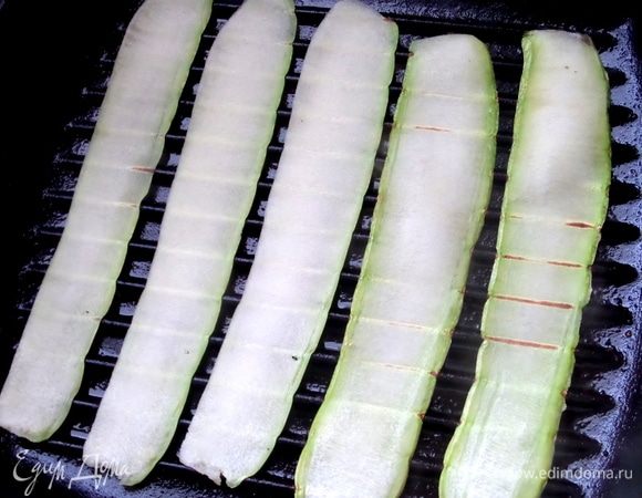 Смазать маслом  сковороду-гриль и положить на нее дольки кабачка.