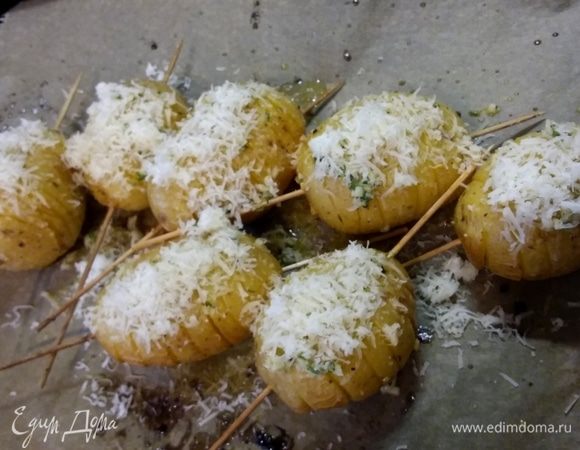 Надеть на руку перчатку и тщательно втереть часть смеси в картофельные проемы. Отправить в заранее разогретую до 200°C духовку (желательно с поддувом) сначала на 15–20 минут. Затем достать противень (картошка за это время немного раскроется) и выложить на него остатки чесночной смеси. Посыпать тертым пармезаном и запекать до готовности. Время приготовления зависит от сорта картошки.