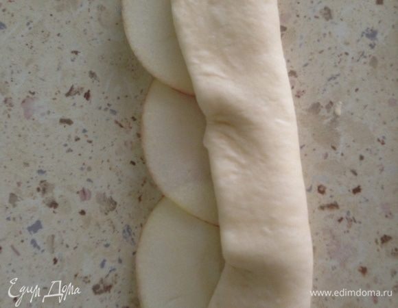 Разделить тесто на небольшие кусочки, каждый раскатать в пласт, нарезать на широкие полоски. Выложить яблоки на тесто так, чтобы края немного вылезали за тесто. Закрыть нижнюю часть яблок тестом.