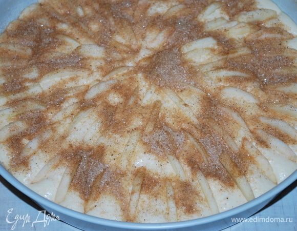 Смазываем форму маслом и посыпаем манной крупой, чтобы пирог легко было снять с формы после выпекания. Выливаем тесто в форму, выкладываем сверху яблоки. Смешиваем столовую ложку сахара с корицей, посыпаем пирог сверху. Выпекаем при температуре 170°C примерно 45 минут.