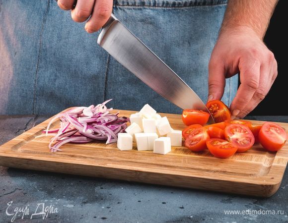 Помидоры черри разрежьте пополам, сыр фета нарежьте кубиками, а красный лук — полукольцами.