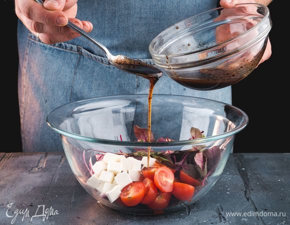 Выложите в салатник помидоры черри, листья салата, лук и сыр, заправьте заправкой.