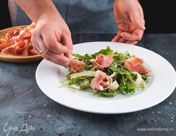 На сервировочную тарелку выложите руколу с грушей, сверху выложите ветчину.