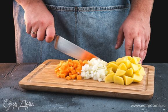 Куриный бульон поставьте на огонь и доведите до кипения. Очистите и нарежьте овощи: репчатый лук и морковь нарежьте мелкими кубиками, картофель — крупными.