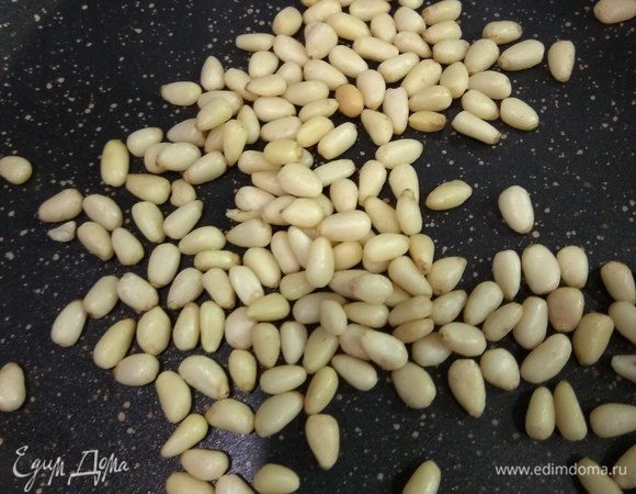 Пока слегка поджарим кедровые орешки на сухой сковороде. Вымоем и подсушим салатные листья и руколу. И сделаем заправку.