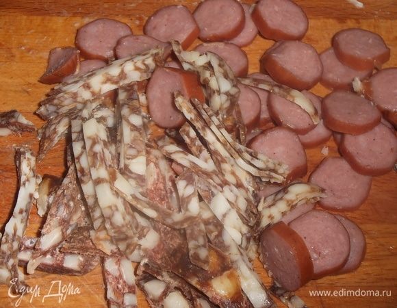 Нарезать любую копченую колбасу. Отправить вместе с мясом в бульон.