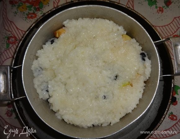 Последним слоем должен быть рис. Поставить кастрюлю в сковороду с горячей водой. Накрыть кастрюлю крышкой и поставить сковороду с кастрюлей в духовку, разогретую до 180°C, на 15–20 минут.