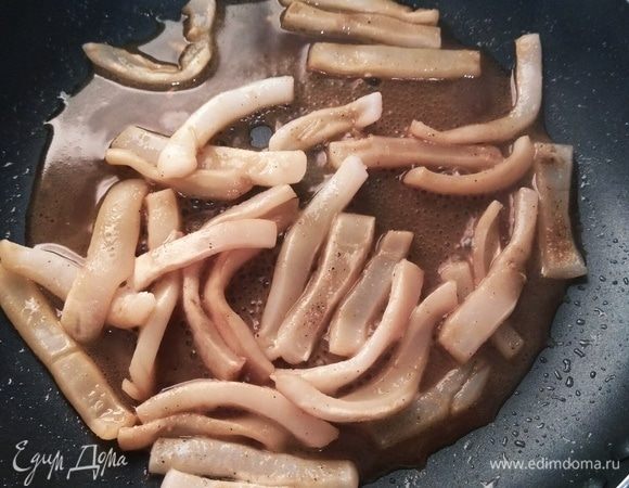 Кальмары выкладываем в сковороду, добавляем сушеный чеснок и соевый соус. Жарим  кальмары до мягкости. За 2 минуты до готовности накрываем сковородку крышкой и немного тушим блюдо.