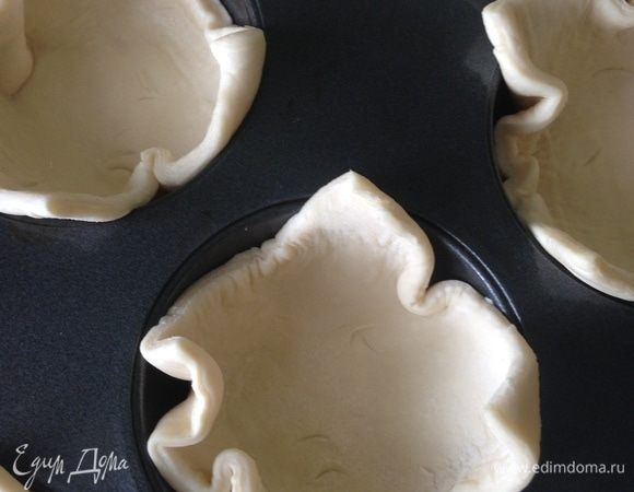 Слоеное тесто разморозить и разрезать на 8 квадратиков. Форму для кексов смазать растительным маслом, положить в ячейки квадратики теста.