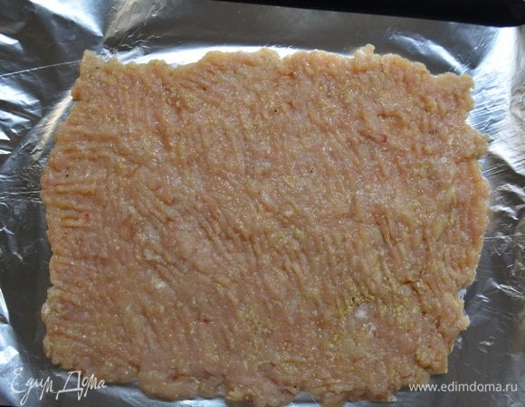 Противень застелить фольгой. Выложить фарш и выровнять тонким слоем в виде прямоугольника.