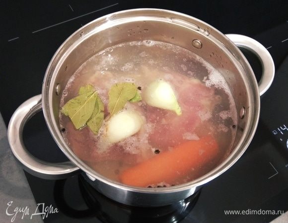 Готовим бульон. Промываем два куриных бедра, чистим морковь и половинку луковицы. Кладем все это в кастрюлю, доводим до кипения, убавляем огонь до минимального уровня, добавляем соль, перец горошком и лавровый лист. Варим примерно 25 минут.