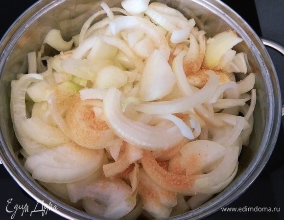 В разогретую кастрюлю (либо в глубокую сковородку) наливаем масло. Репчатый лук нарезаем полукольцами и кладем в кастрюлю. Добавляем сахар, перемешиваем. Накрываем крышкой и тушим в собственном соку примерно 30–35 минут. Не забываем периодически перемешивать лук.