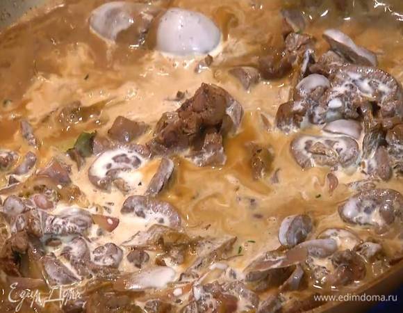 Вернуть почки в сковороду к луку и грибам, через сито влить воду, в которой замачивались грибы, дать жидкости немного выпариться, затем влить сливки, все перемешать и слегка все прогреть.