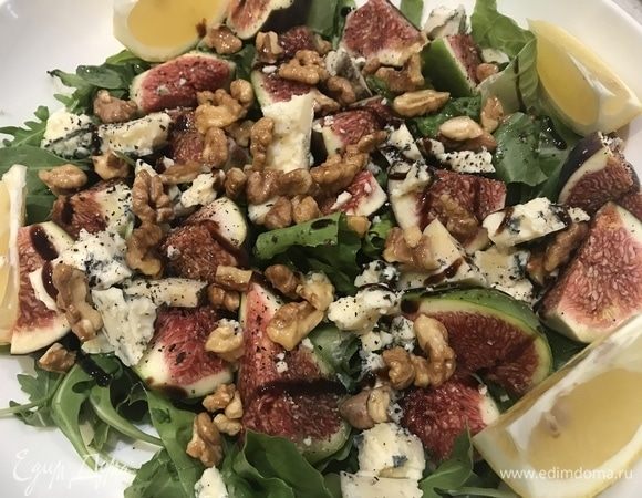 Выкладываем на руколу сначала инжир, затем сыр и посыпаем грецкими орехами. Лимон кладем по краям.