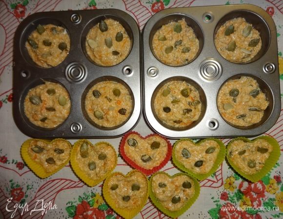Формочки для кексов смазать растительным маслом. Выложить тесто в формочки на 2/3 объема. В каждый кекс вложить по несколько штук целых тыквенных семечек.