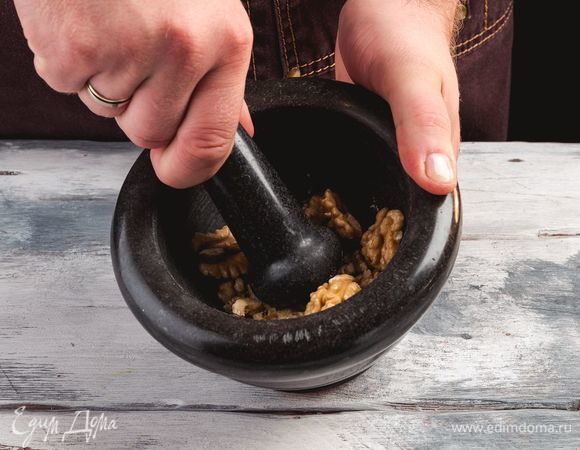 Измельчите грецкие орехи в ступке.