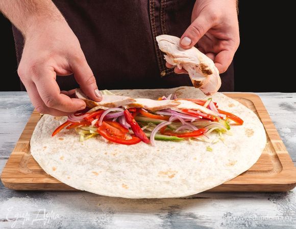 Выложите на лаваш листья салата, мясо и овощи.